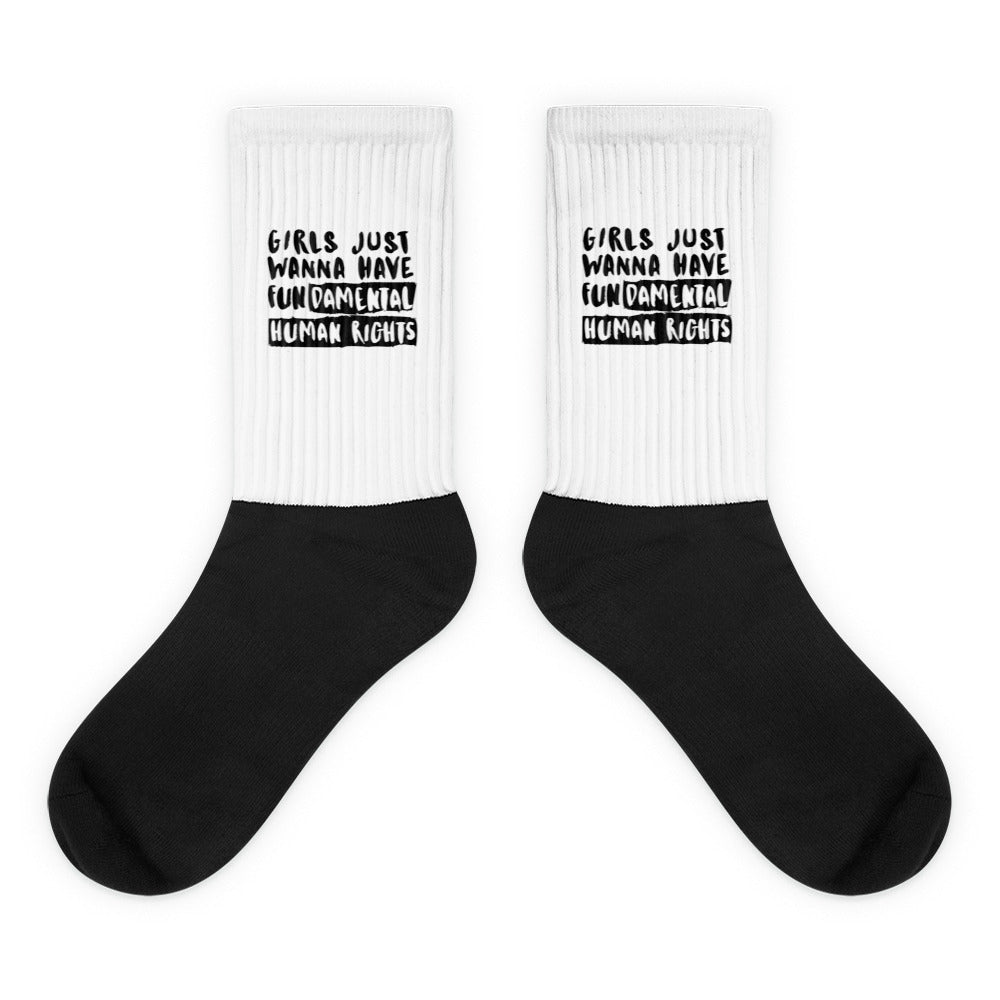 Pair of black-and-white socks reading “GIRLS JUST WANNA HAVE FUNDAMENTAL HUMAN RIGHTS”