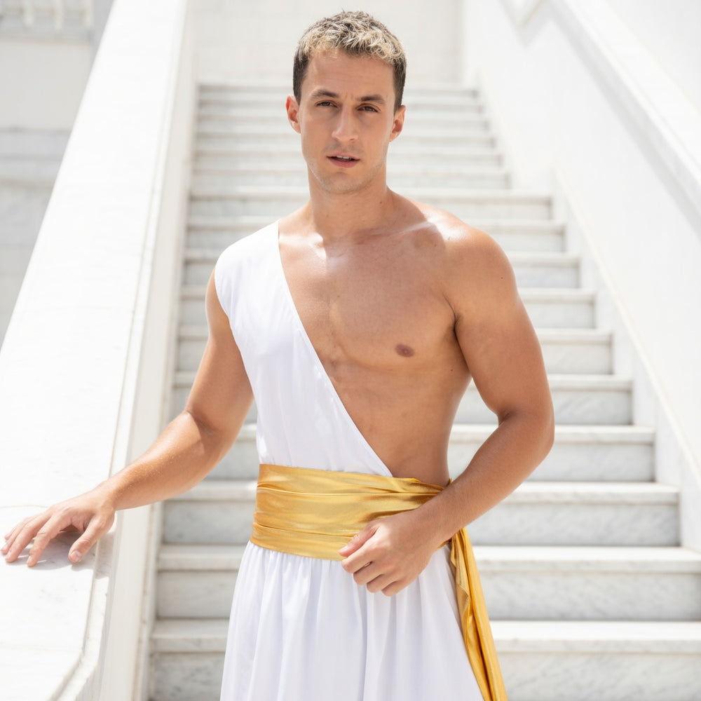Model wearing a white one-shoulder gladiator tunic with a gold waist sash on stairs