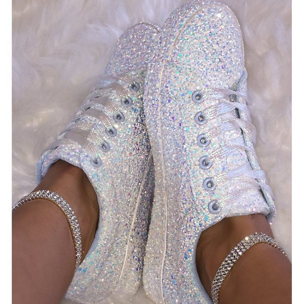 Top view of glitter-covered white lace-up sneakers worn with rhinestone ankle cuffs