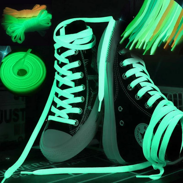 Glowing green shoelaces threaded through black high-top sneakers, with loose laces beside them