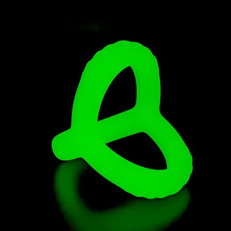 Neon-green, three-loop penis ring glowing against a black background