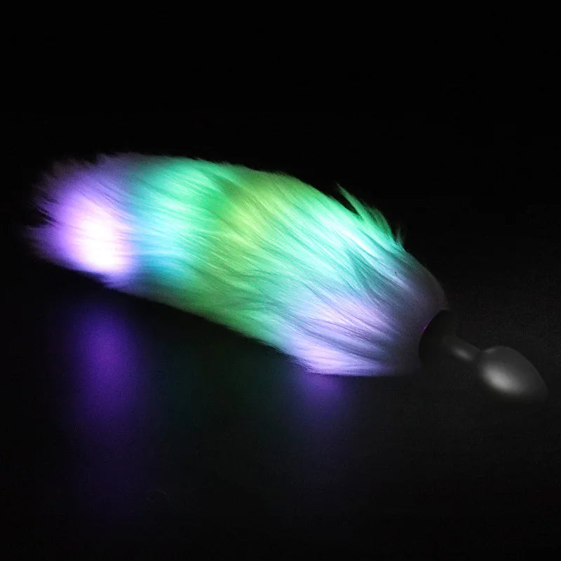 Glowing multicolor furry tail attached to a black anal plug, shown on a dark surface