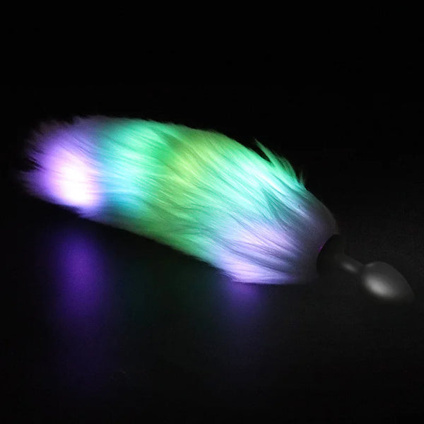 Glowing multicolor furry tail attached to a black anal plug, shown on a dark surface