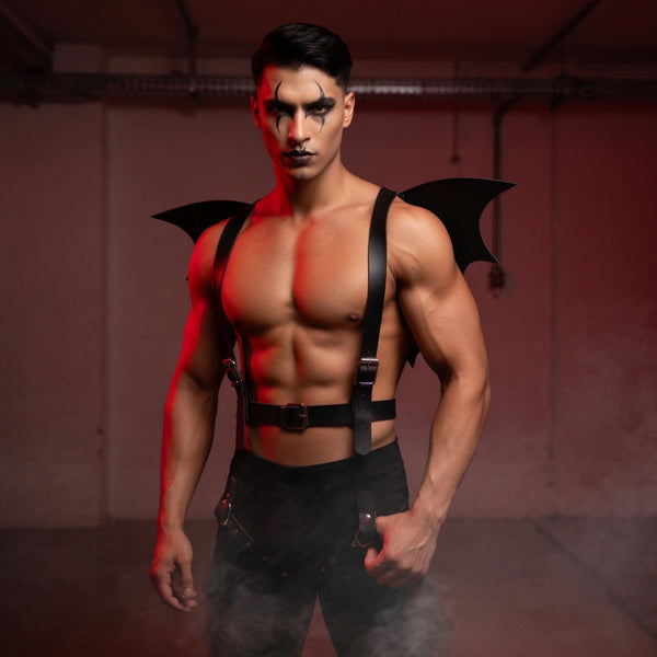 Front-facing model wearing a black leather harness with bat-wing panels