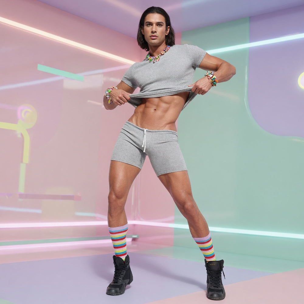 Model lifts a gray crop tee above matching sweatshorts, revealing the midriff, with rainbow socks