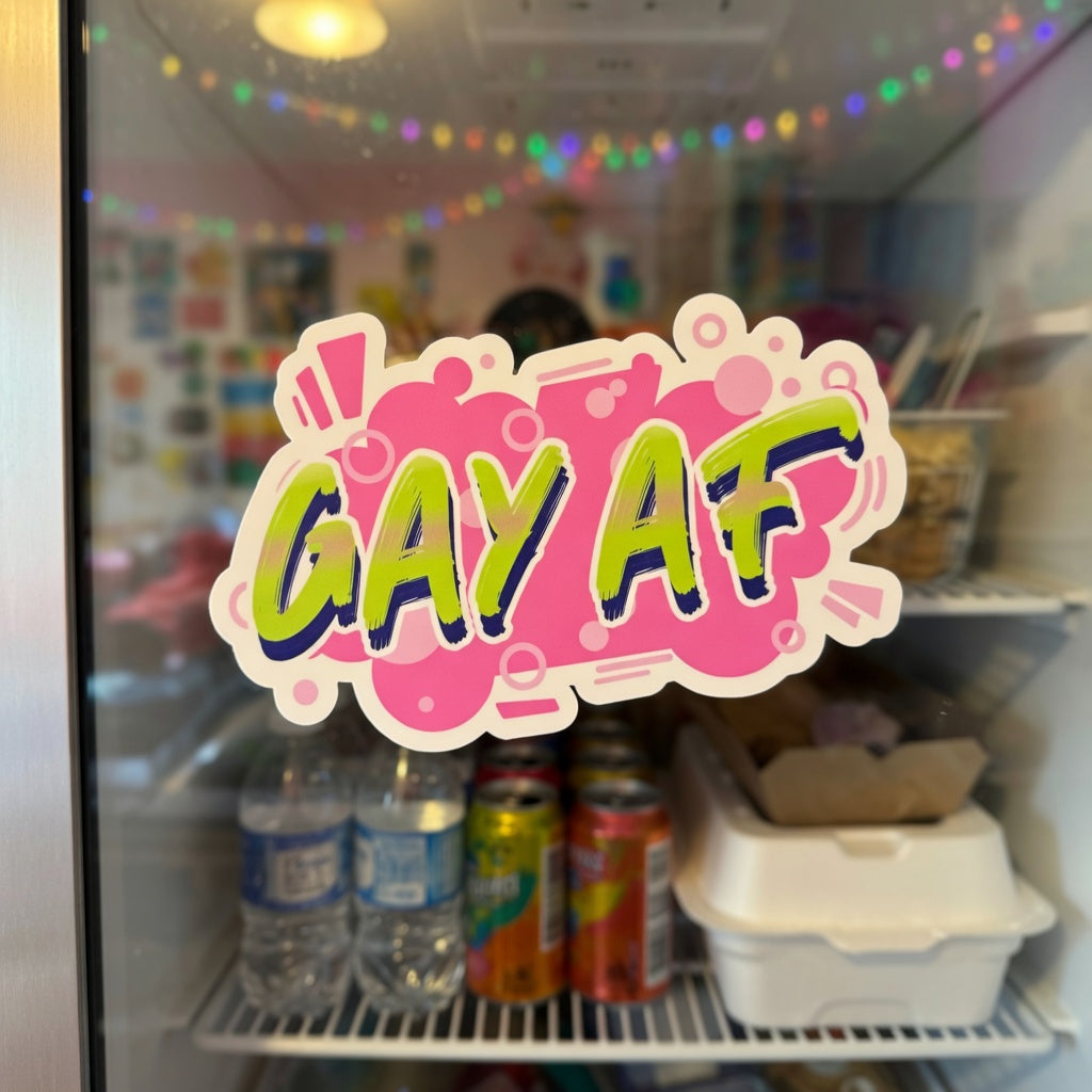 “Gay AF” bubble-free sticker on a glass fridge door, with water bottles, cans, and takeout containers behind rainbow reflections.