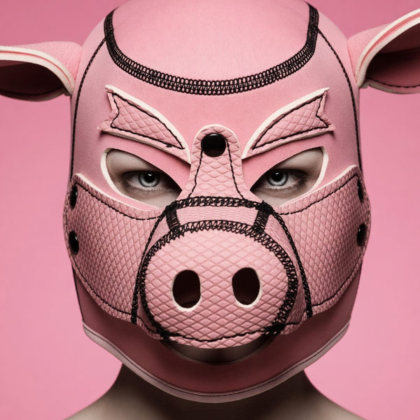 Close-up of a pink pig BDSM hood with mesh panels, snout, ears, and eye openings