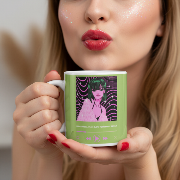 Person holding green ceramic mug with illustrated figure; mug with “Guaranteed, I Can Blow Your Mind...Mwah!” design