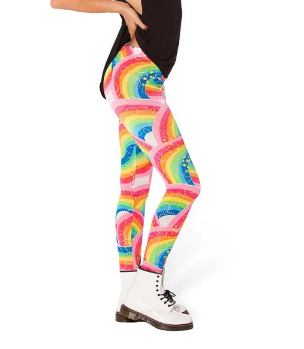 Side view of a model wearing bright rainbow-patterned leggings with white ankle boots
