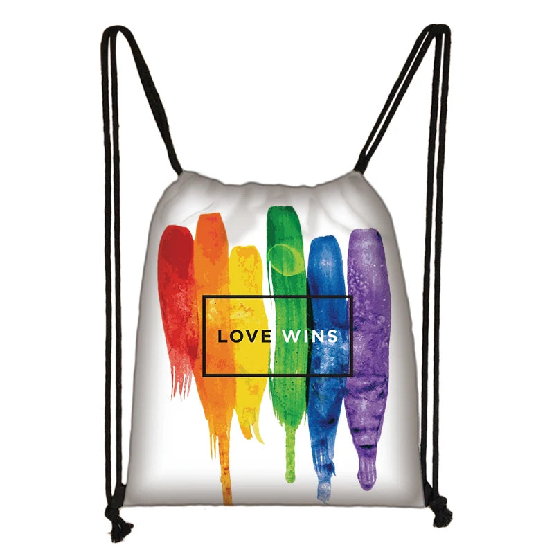 White drawstring bag with rainbow brushstrokes and a boxed “LOVE WINS” design