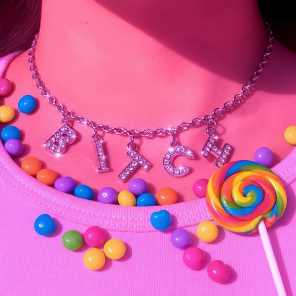 Crystal-studded BITCH letter choker on a pink top with colorful candy accents