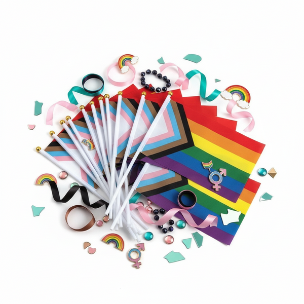Flat lay of handheld rainbow and Progress Pride flags with ribbons and gender-symbol decorations