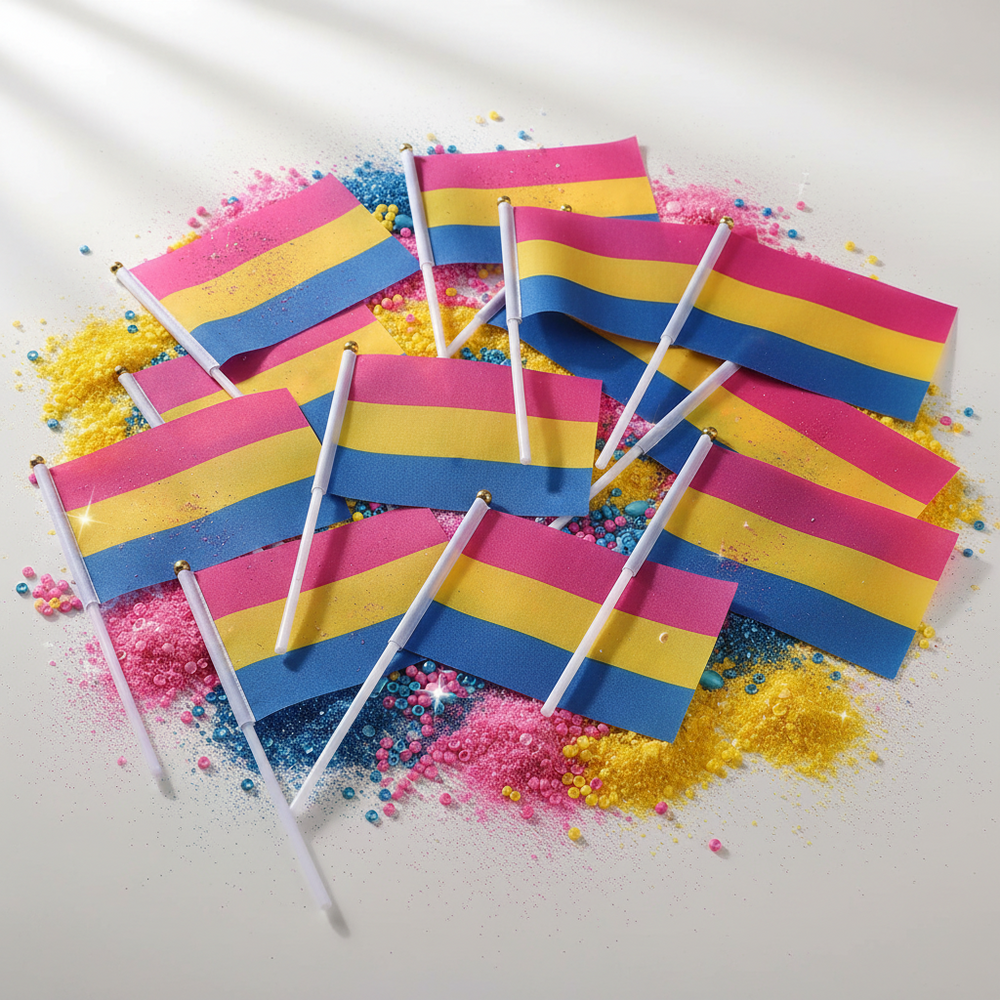 Several handheld pansexual pride flags scattered on colorful powder and bead confetti