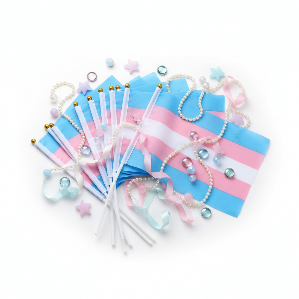 Flat lay of transgender pride flags on white sticks with pastel ribbons, pearls, beads, and confetti