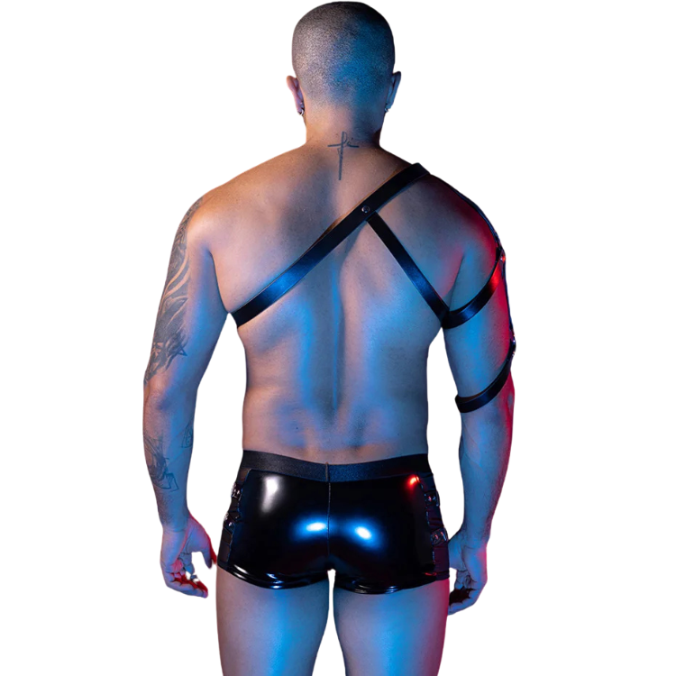 Rear view of a tattooed model wearing a black leather harness and glossy shorts