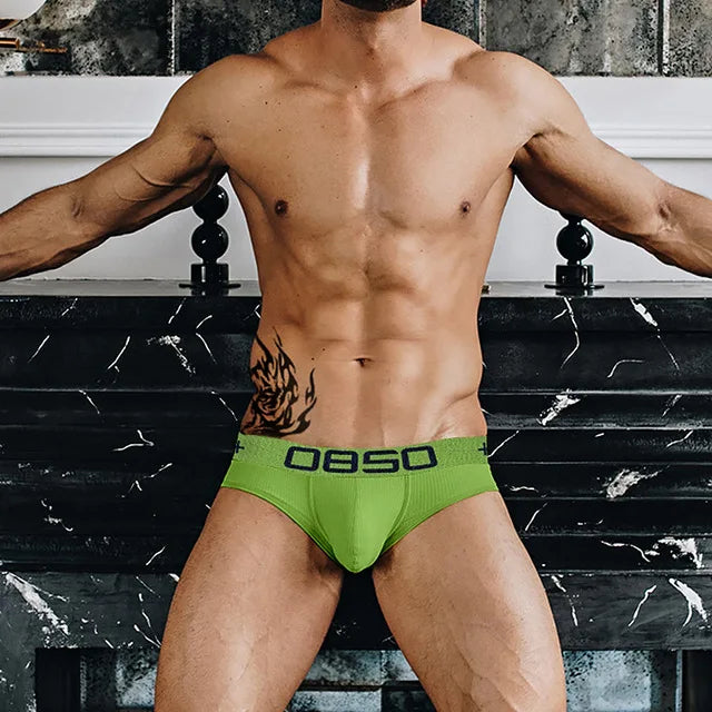 Model wearing bright green OBSO briefs with a dark logo waistband
