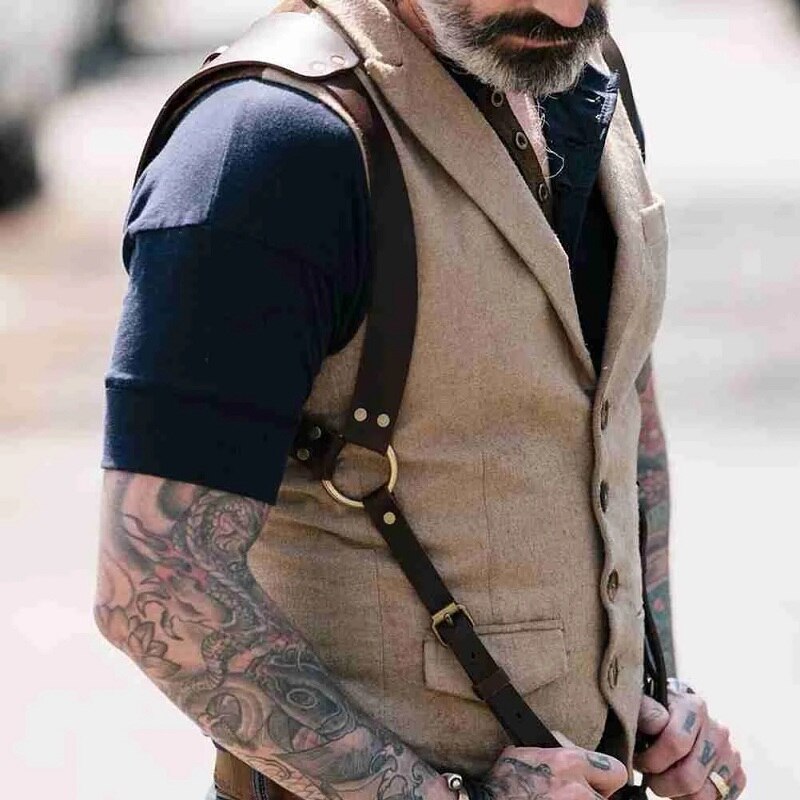 Person wearing black leather clip-on shoulder suspenders over a tan vest