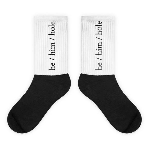 Pair of black-and-white crew socks labeled “he / him / hole” on white cuffs