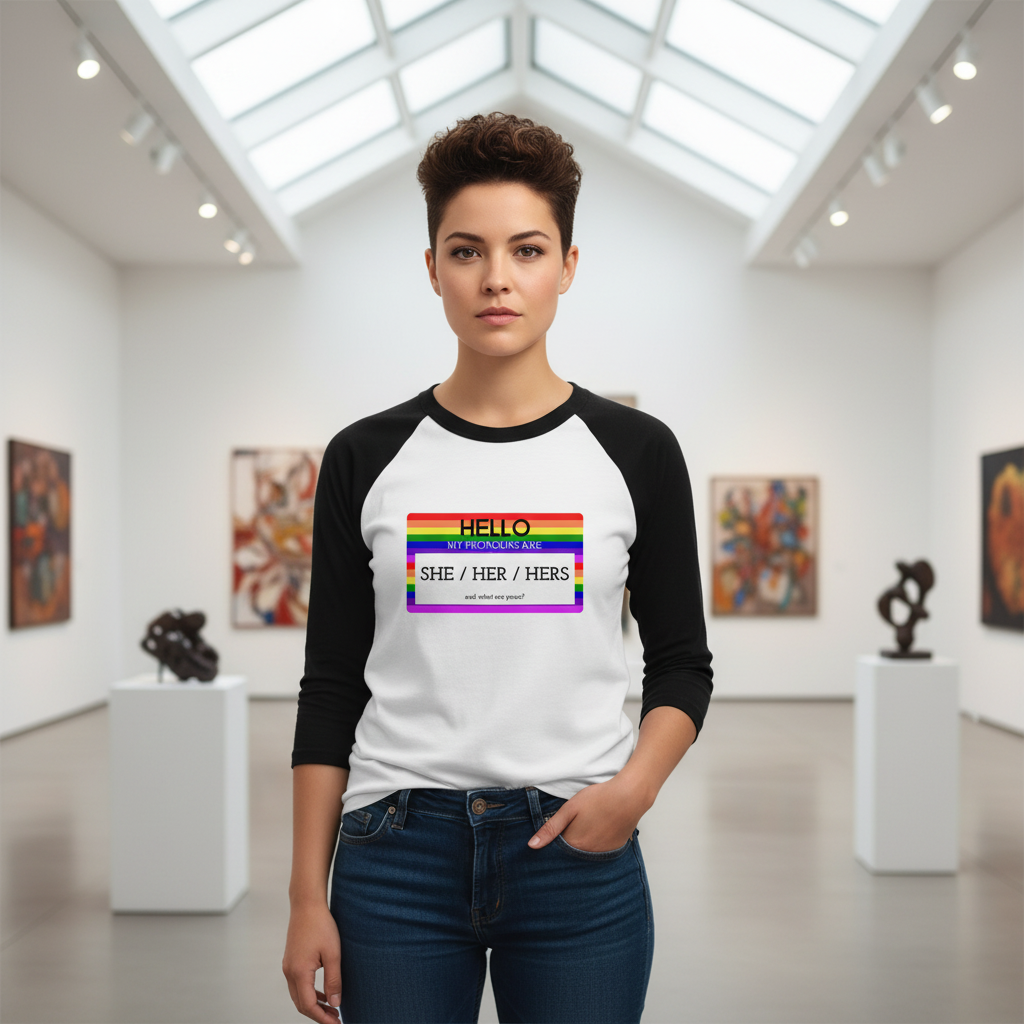 3/4 sleeve raglan shirt with "Hello My Pronouns Are She / Her / Hers" and a rainbow name tag