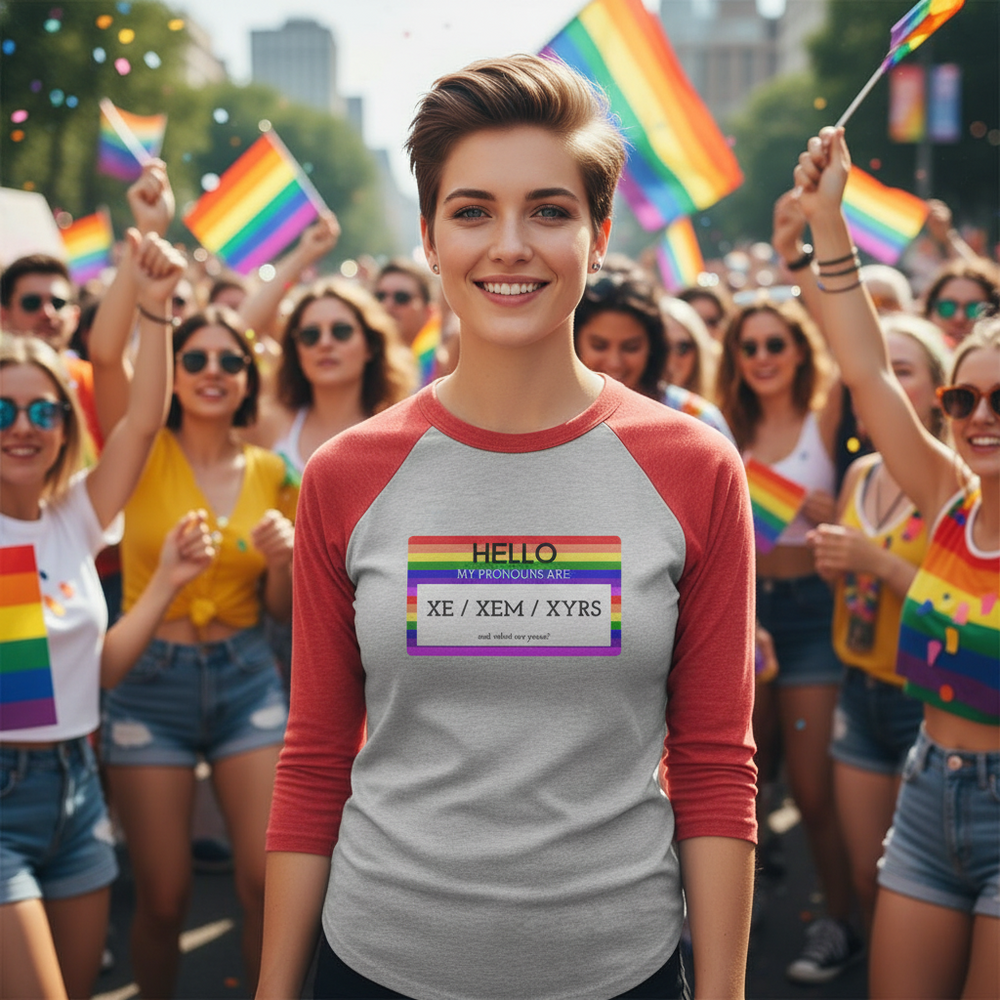 3/4 sleeve raglan shirt reads “Hello My Pronouns Are Xe / Xem / Xyrs.” person smiles at Pride; colorful crowd, flags behind