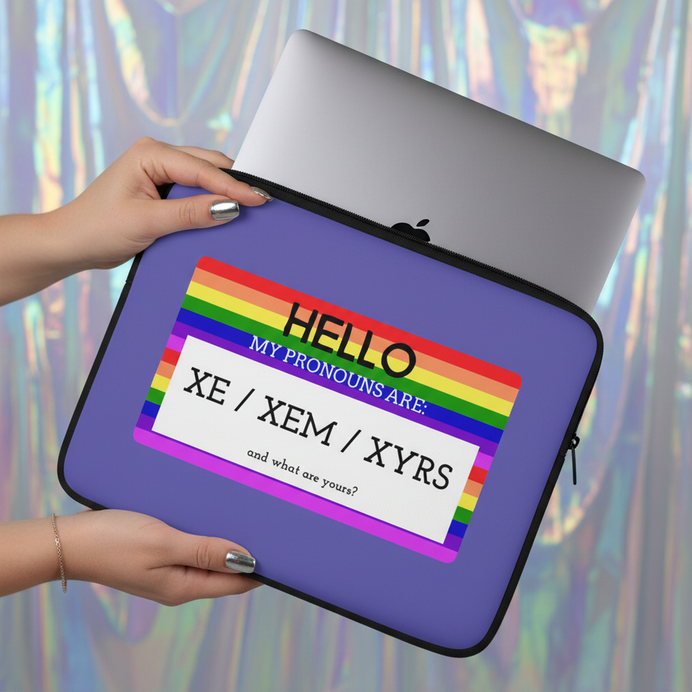 Laptop sleeve reads "Hello My Pronouns Are Xe / Xem / Xyrs" on a rainbow-bordered tag