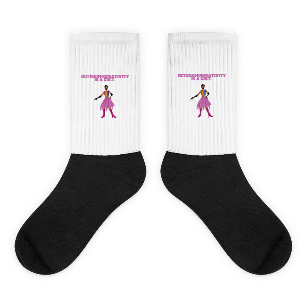 Pair of black-and-white socks reading “HETERONORMATIVITY IS A CULT.” with a colorful figure
