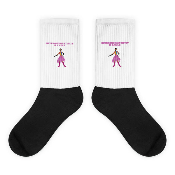 Pair of black-and-white socks reading “HETERONORMATIVITY IS A CULT.” with a colorful figure