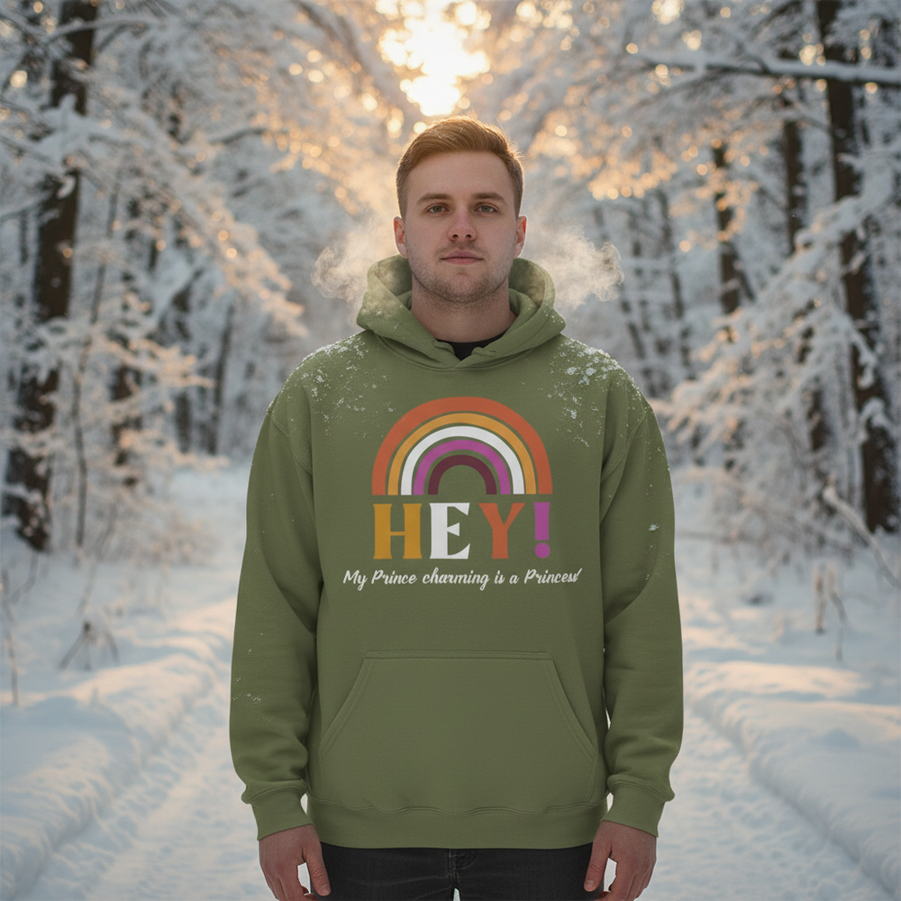 Front-facing person wearing an olive hoodie with a rainbow and “HEY!” graphic in a snowy forest