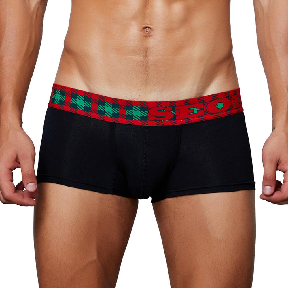 Front view of a model wearing black boxer briefs with a red and green plaid waistband reading “HO HO”