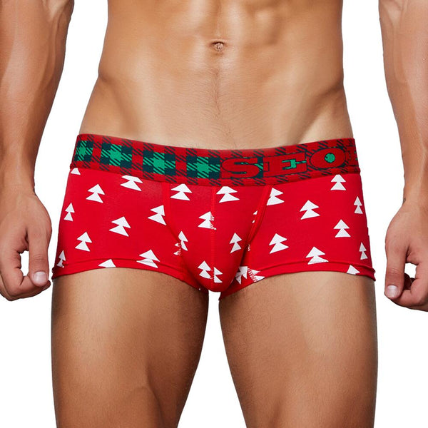 Front view of a model wearing red boxer briefs with white Christmas trees and a plaid waistband