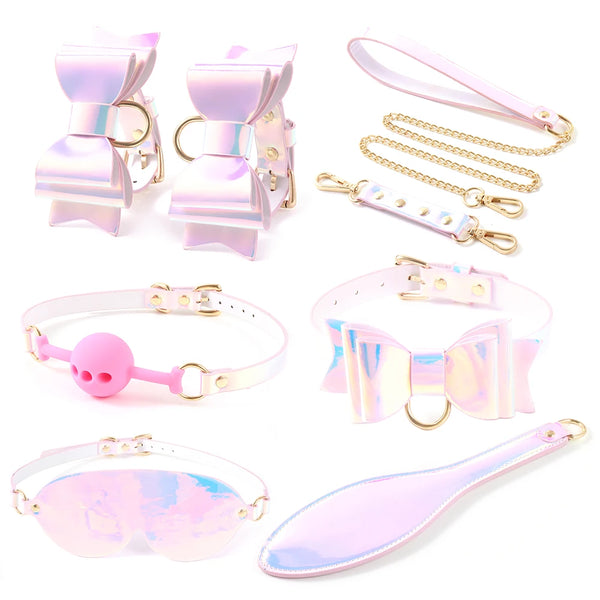 Flat lay of a pastel holographic BDSM kit with cuffs, collar, mask, ball gag, chain, and paddle