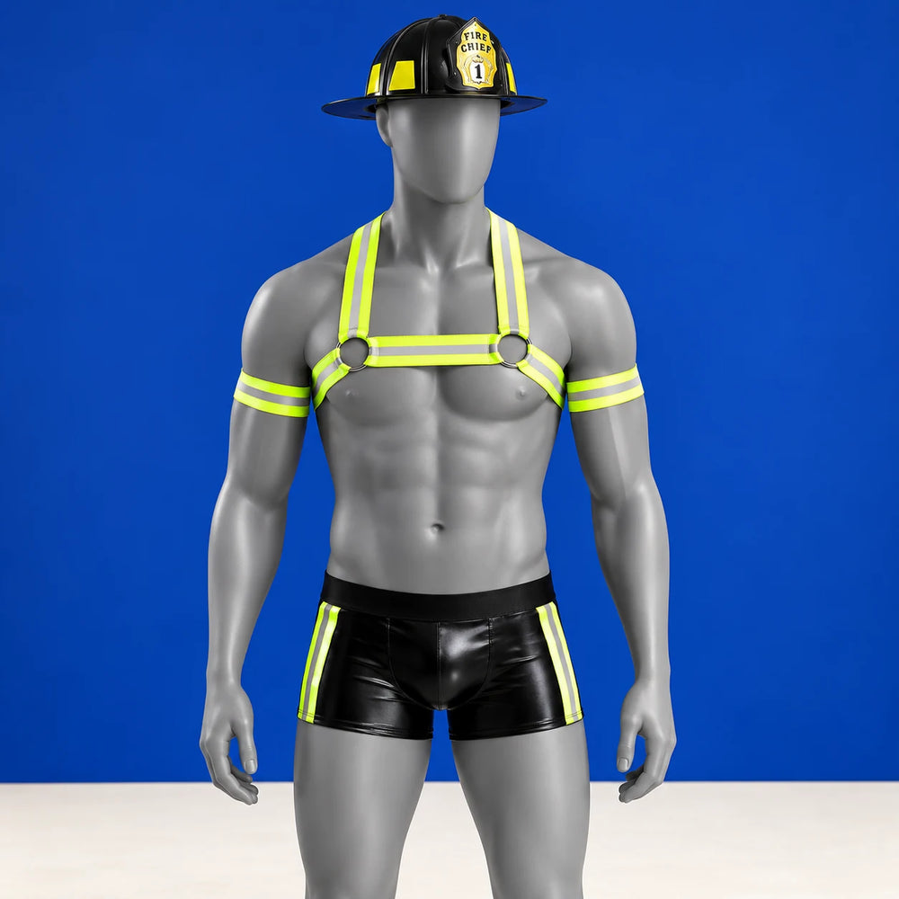 Kinky Fireman costume on a grey mannequin with black helmet, neon-yellow harness, arm bands and black short trunks against cobalt.