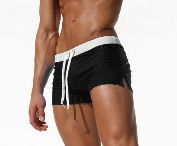 Model wearing black low-rise swim shorts with a white waistband and drawstring
