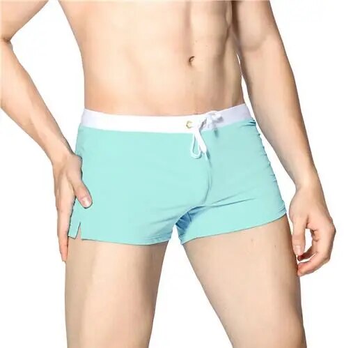 Model wearing mint green swim shorts with a white drawstring waistband