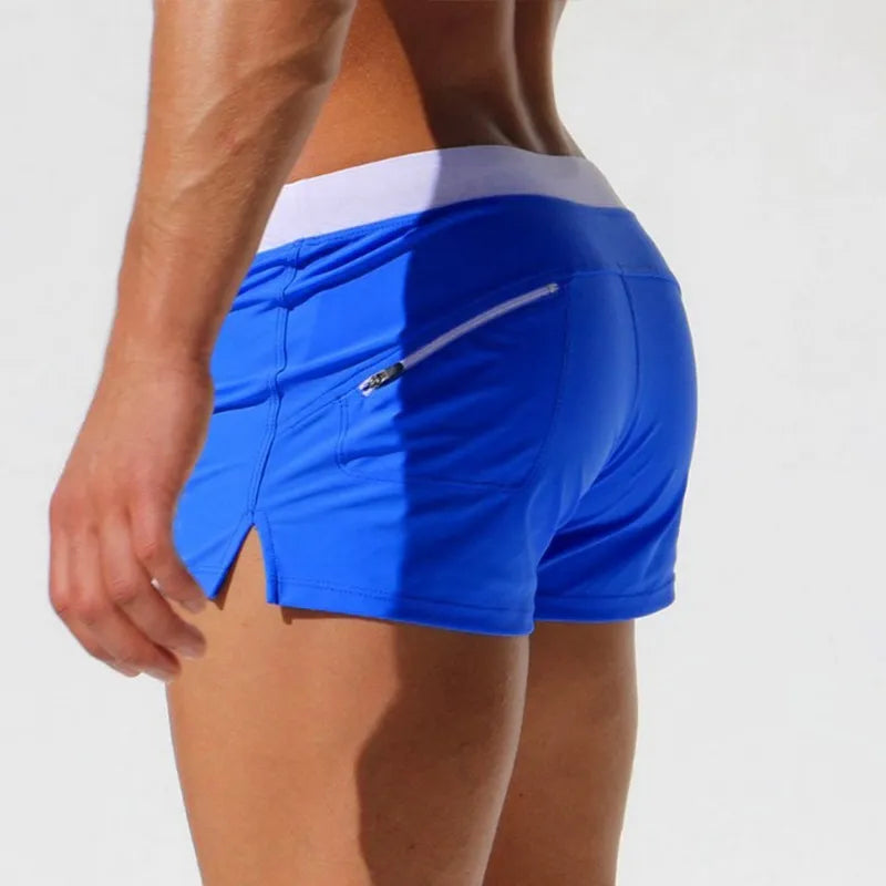 Rear view of bright blue swim shorts with a white waistband and zippered back pocket