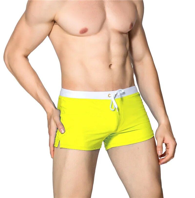 Neon yellow men's swim shorts with white waistband and drawstring, shown on a model