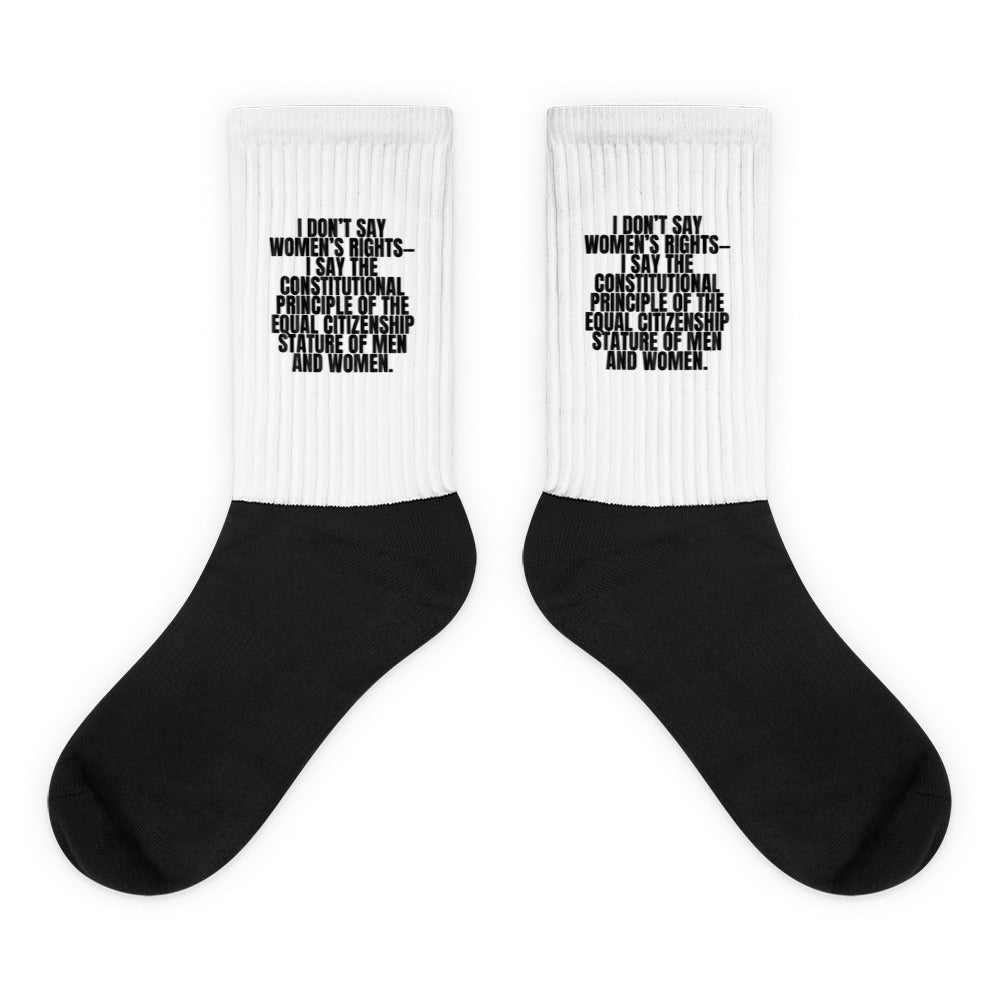 Pair of black-and-white crew socks with a feminist quotation printed on the cuffs