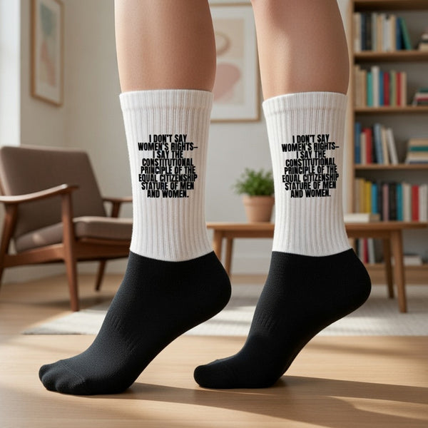 White-and-black crew socks worn on feet, printed with a women's rights statement
