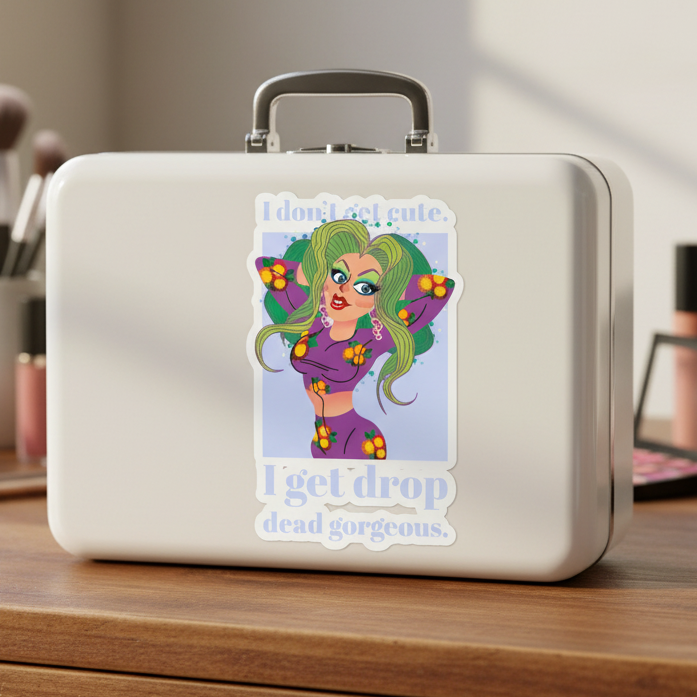 White lunchbox on wood with "I Get Drop Dead Gorgeous Bubble-Free Sticker"—cartoon femme in green hair, glam makeup