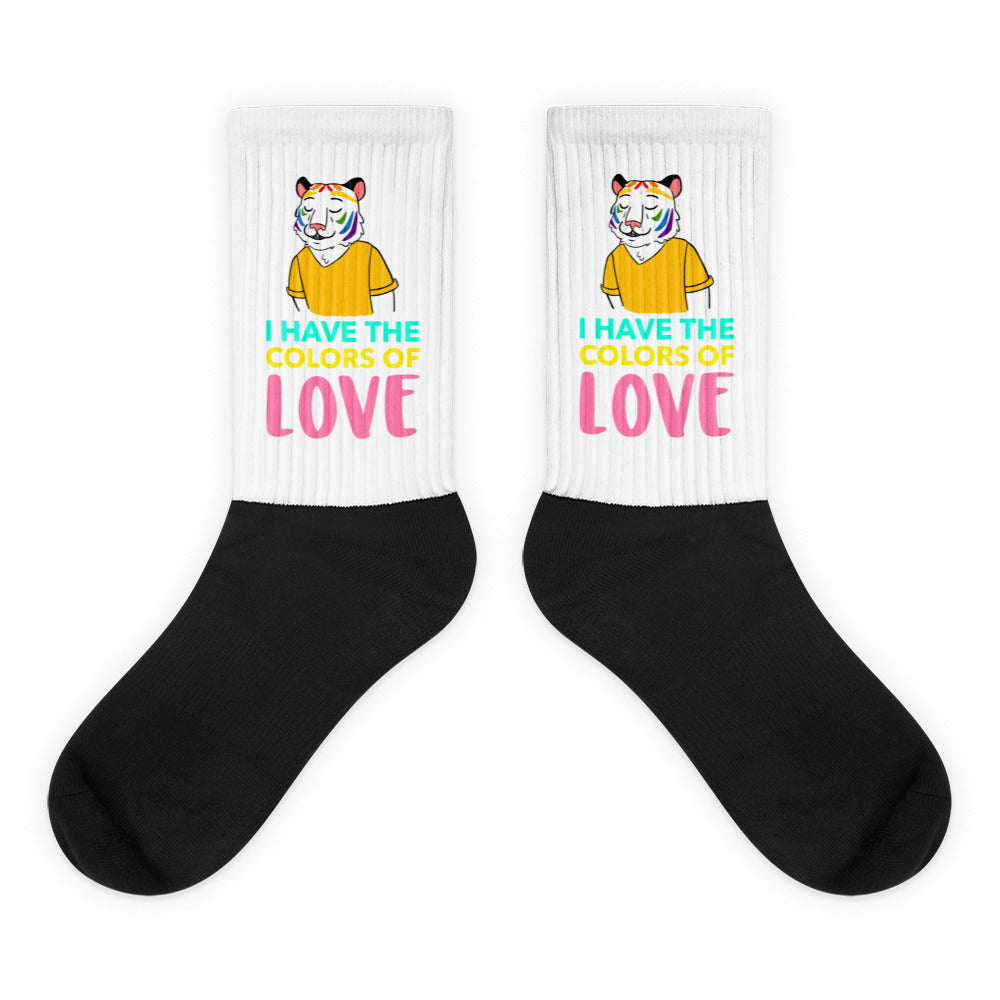 Pair of black-and-white crew socks with rainbow tiger graphics and “I HAVE THE COLORS OF LOVE” text