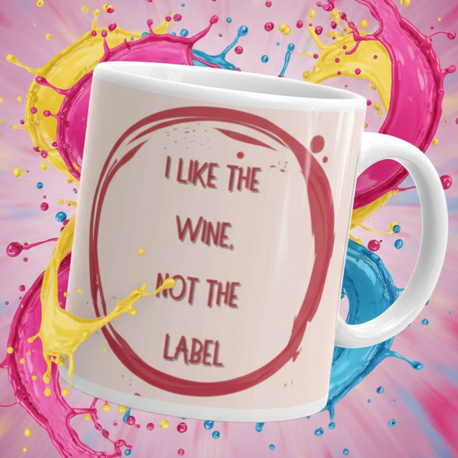 Angled white mug reading “I LIKE THE WINE, NOT THE LABEL” over colorful paint splashes
