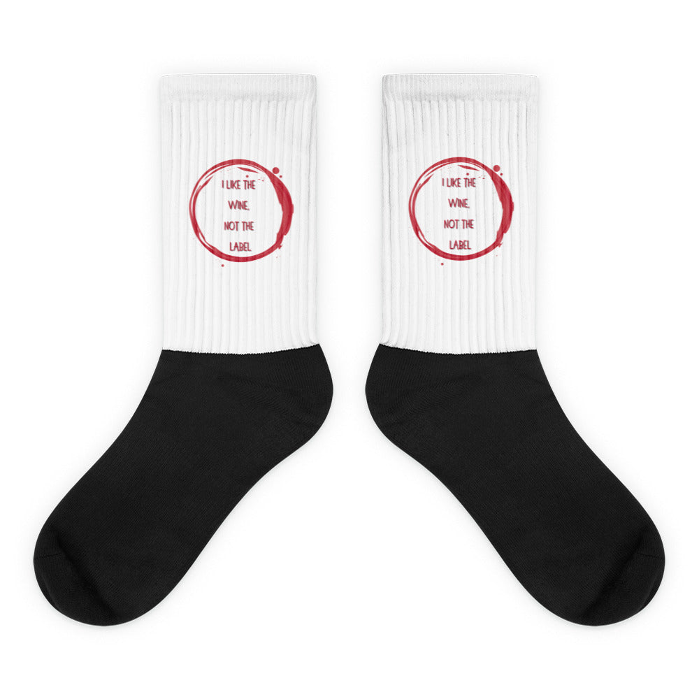 Pair of black-and-white crew socks with red wine-ring graphics and “I LIKE THE WINE NOT THE LABEL” text