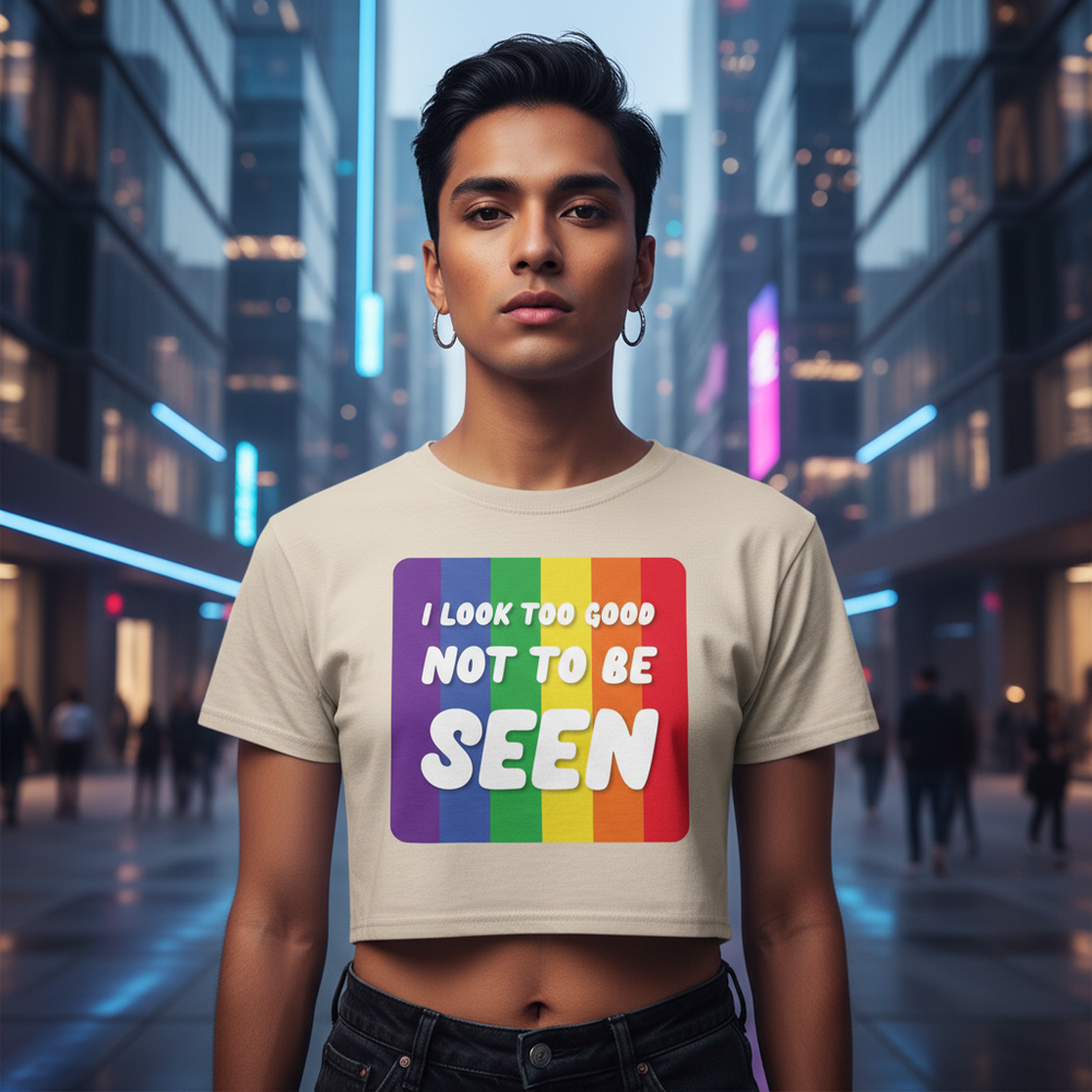 Crop top with "I Look Too Good" slogan and rainbow-striped square, worn by a confident person in a neon-lit city at dusk