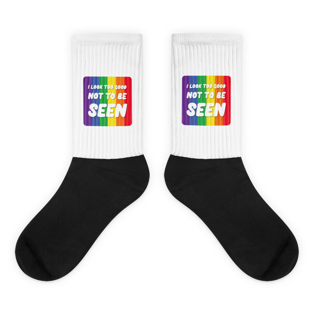 Pair of black-and-white crew socks with rainbow panels reading “I LOOK TOO GOOD NOT TO BE SEEN”