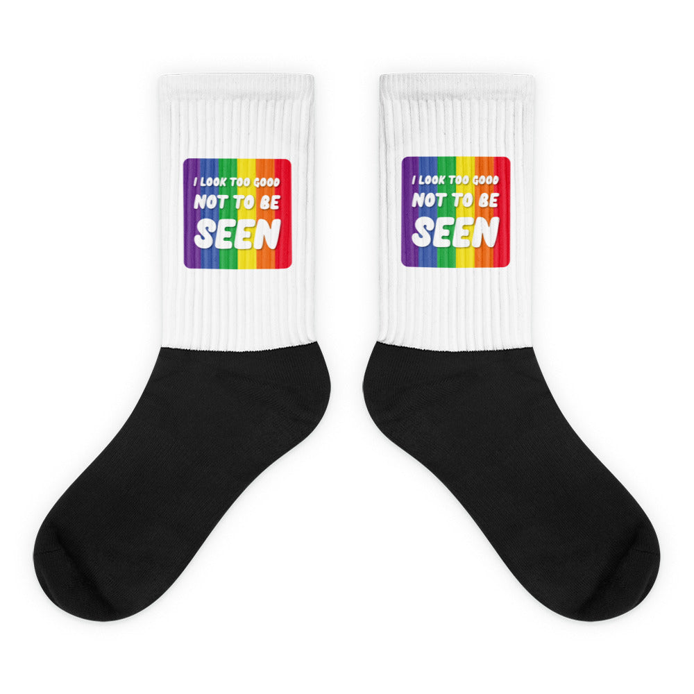 Pair of black-and-white crew socks with rainbow panels reading “I LOOK TOO GOOD NOT TO BE SEEN”