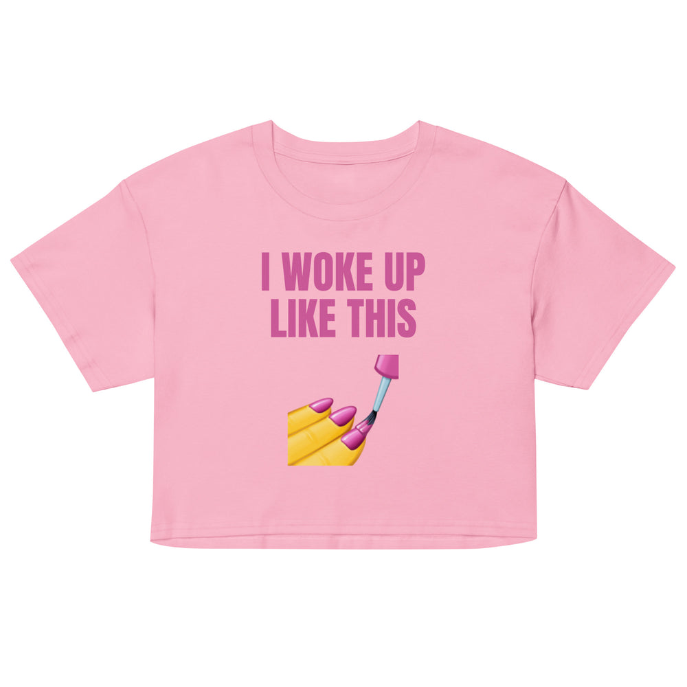 Front view of a pink crop top reading “I WOKE UP LIKE THIS” above a nail-painting graphic