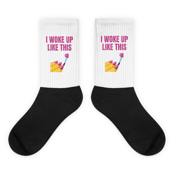 Pair of black-and-white socks reading “I WOKE UP LIKE THIS” with a nail-painting graphic