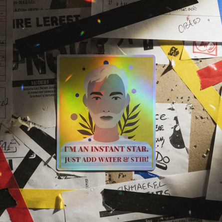 Holographic vinyl sticker with a short-haired illustrated face and rainbow shimmer, reading IM AN INSTANT STAR