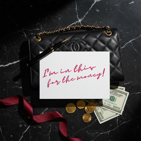 “Im In This For The Money” postcard on marble with bold red script, next to black quilted purse, gold chain, fountain pen