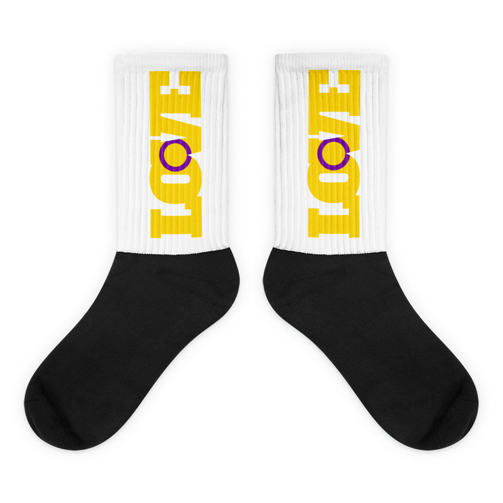 Pair of white ribbed crew socks with black feet and yellow-and-purple vertical graphics